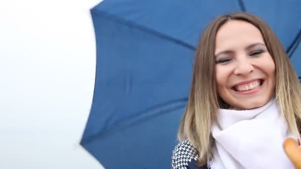 Smiling young woman playing with her blue umbrella — Stock Video