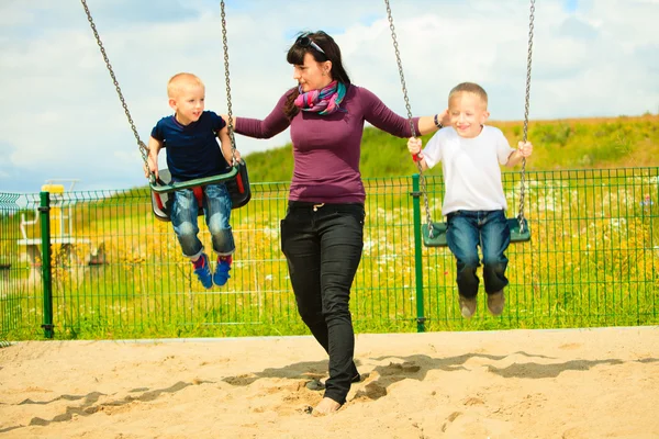 Madre e bambini si divertono su un'altalena fuori — Foto Stock