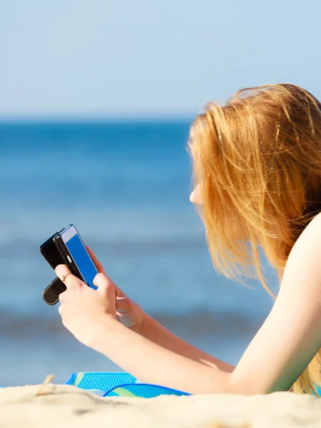 Sommar semester Flicka med telefon garvning på stranden — Stockfoto