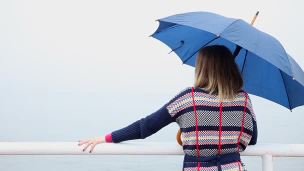 На спине молодой женщины с голубым зонтиком — стоковое видео