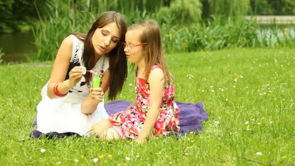 Jonge vrouw en kind zeepbellen blazen — Stockvideo