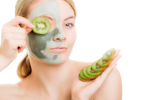 Woman in clay mask on face covering eye with kiwi — Stock Photo, Image