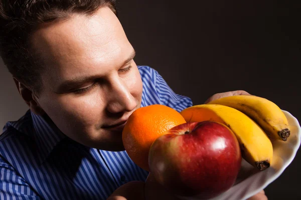 Счастливый молодой человек нюхает фрукты . — стоковое фото