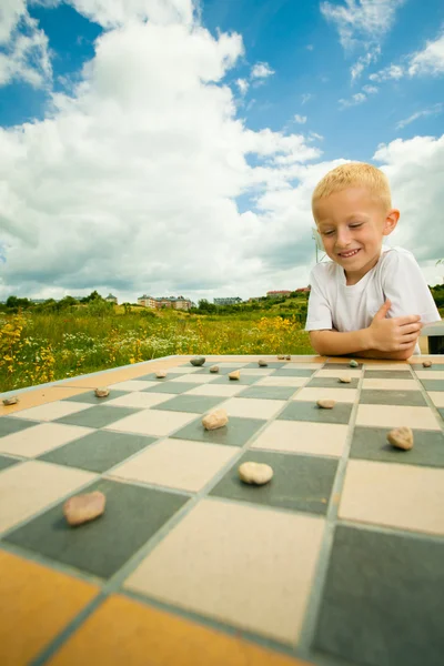 Child playing draughts or checkers board game outdoor — Stock Photo, Image