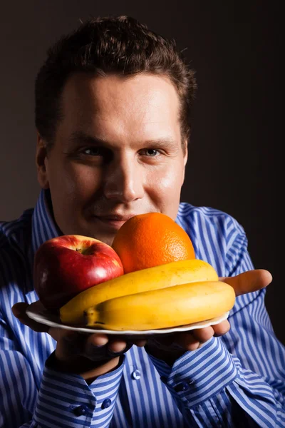 Счастливый молодой человек нюхает фрукты . — стоковое фото
