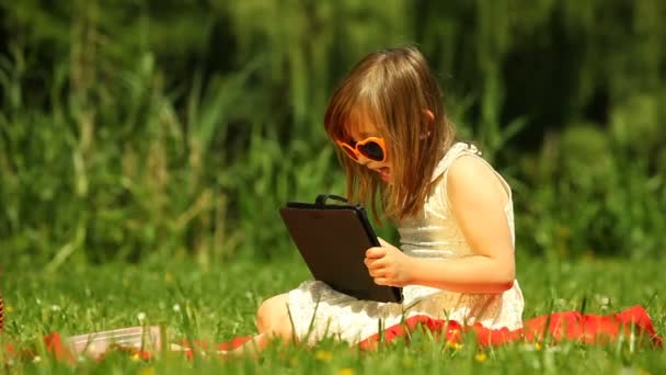 Niña en gafas de sol usando tableta — Vídeo de stock