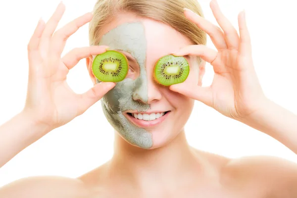 Vrouw in klei masker met kiwi op gezicht — Stockfoto