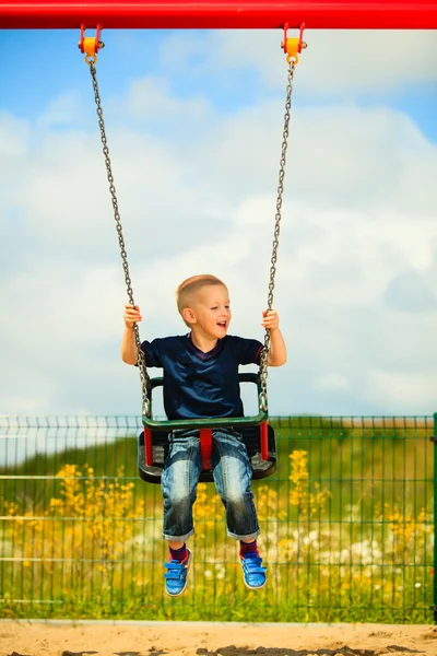 Piccolo bambino biondo divertirsi su un'altalena all'aperto — Foto Stock