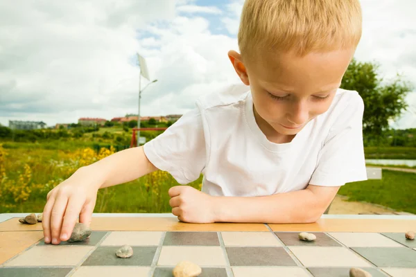 Child playing draughts or checkers board game outdoor — Stock Photo, Image