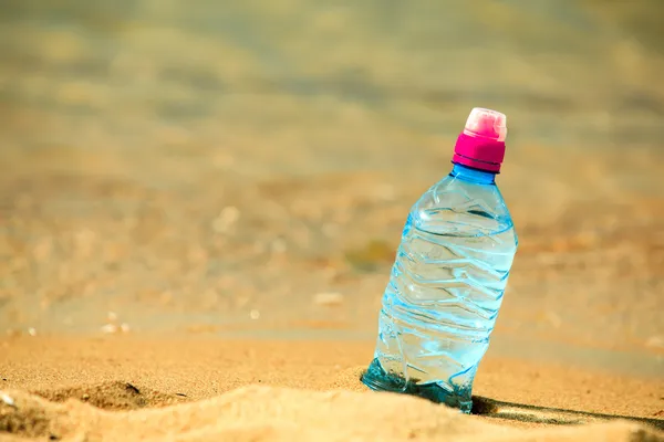 Bottiglia di bevanda acquosa su una spiaggia di sabbia . — Foto Stock