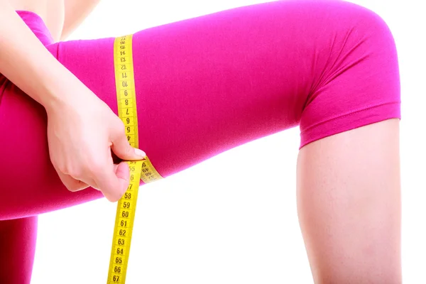 Fitness woman with measure tape measuring her thigh — Stock Photo, Image