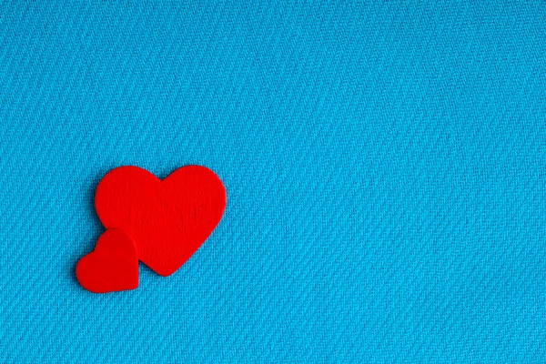 Red wooden decorative hearts on blue cloth background. — Stock Photo, Image