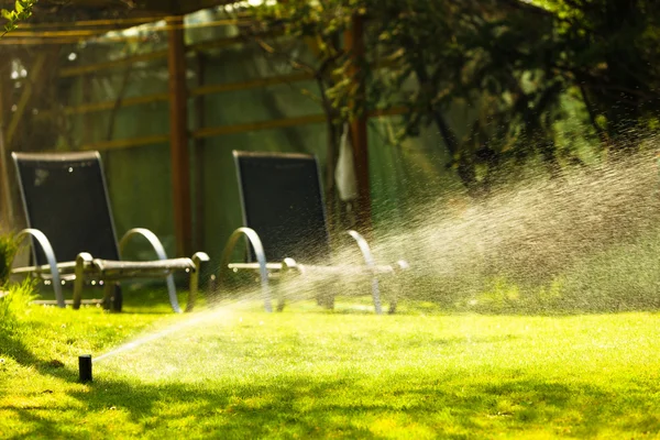 Irroratore per prato spruzzando acqua sull'erba — Foto Stock