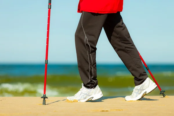 Caminar nórdico. Piernas femeninas senderismo en la playa. —  Fotos de Stock