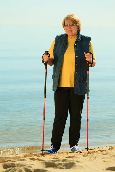 Seniorin beim Nordic Walking am Strand — Stockfoto