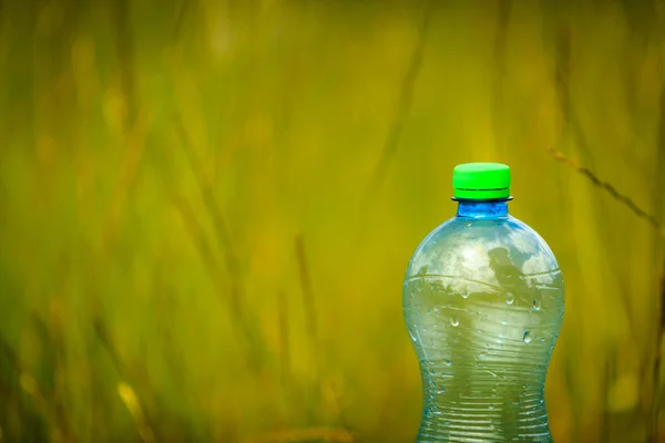 Water bottle on green grass — Stock Photo, Image