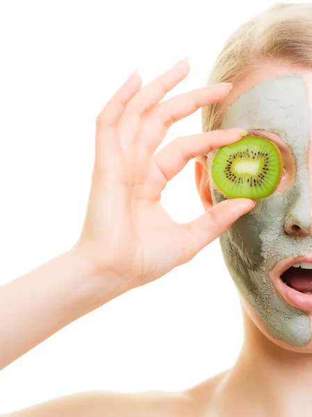 Vrouw in klei masker met kiwi op gezicht — Stockfoto