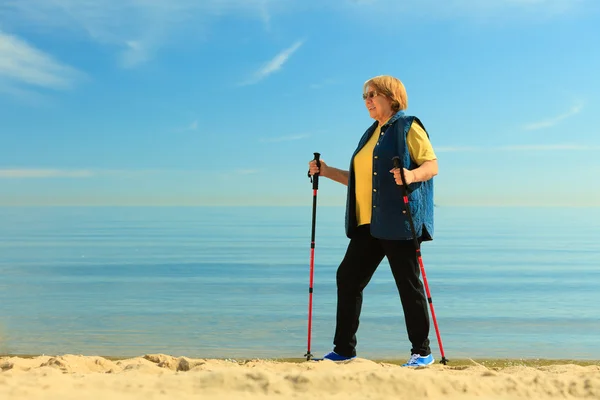 Active senior woman walking on beach — Stock Photo, Image