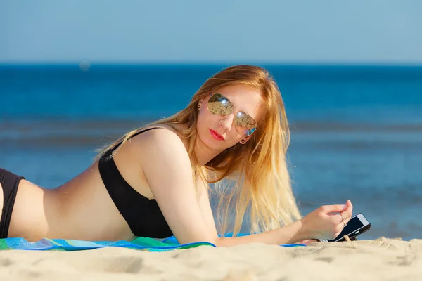 Girl with phone tanning on beach — Stock Photo, Image