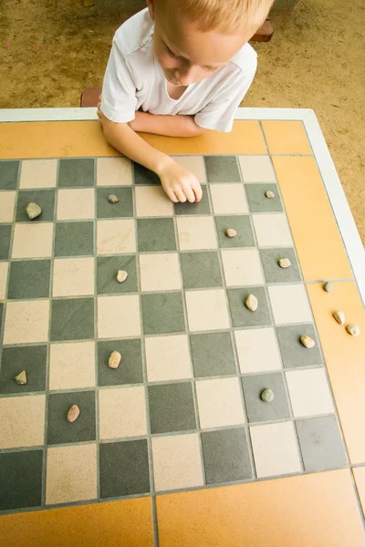 Dítě hrát dárky nebo šachovnice desková hra venkovní — Stock fotografie