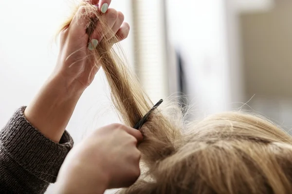 Hairstylist combing female client blond girl in hairdressing salon — Stock Photo, Image