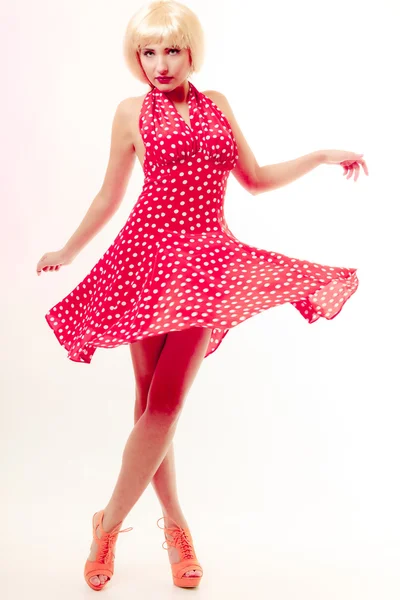 Beautiful pinup girl in blond wig and retro red dress dancing. Party. Royalty Free Stock Photos