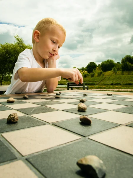 Child playing draughts or checkers board game outdoor — Stock Photo, Image