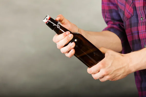 Joven sosteniendo una botella de cerveza en gris —  Fotos de Stock