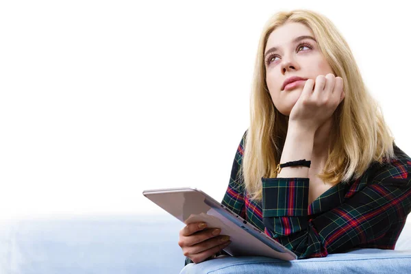 年轻的少女坐在沙发上 一边用平板电脑一边放松地上网 — 图库照片