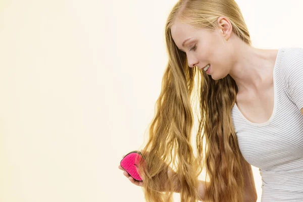 金髪の女の子は長い髪を持っているブラシで 女の子は彼女の髪型をリフレッシュ世話をする ヘアケアのコンセプト — ストック写真