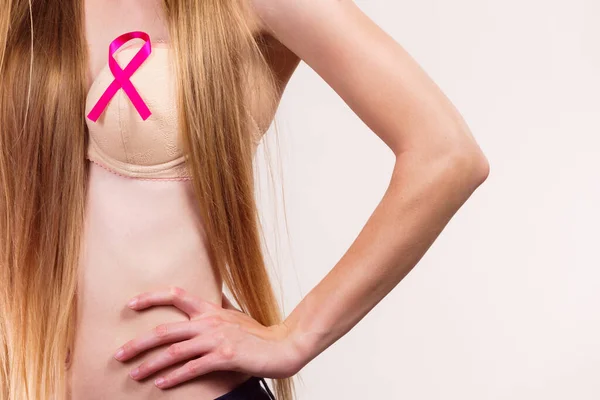 Woman wih pink ribbon on chest. Female wearing bra showing symbol representing awareness, hope and moral support for breast cancer patients.