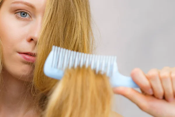 Mulher Loira Com Pente Escovando Seu Cabelo Muito Longo Bagunçado — Fotografia de Stock