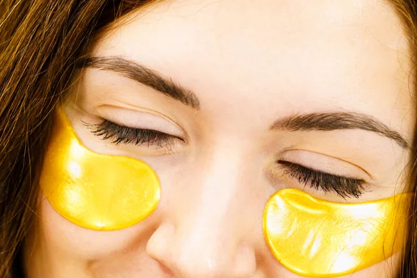 女人用黄金胶原蛋白贴片在眼睛下面 面罩去除皱纹和黑眼圈 女性照顾眼睛周围细嫩的皮肤 美容疗法 — 图库照片