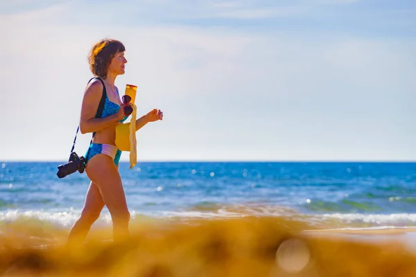 旅行自由概念 穿着比基尼的成熟女性游客 带着相机在海滩上散步 日光浴 享受暑假 — 图库照片