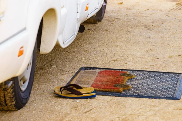 Flip flops on doormat in front of camper car. Travel in motorhome, holidays.