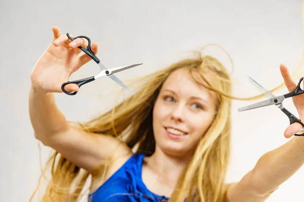 ヘアカットカフヘアケアのコンセプト 長いブロンドの髪の保持はさみを吹いている女の子 作業ツールを示します 通常と薄毛 — ストック写真