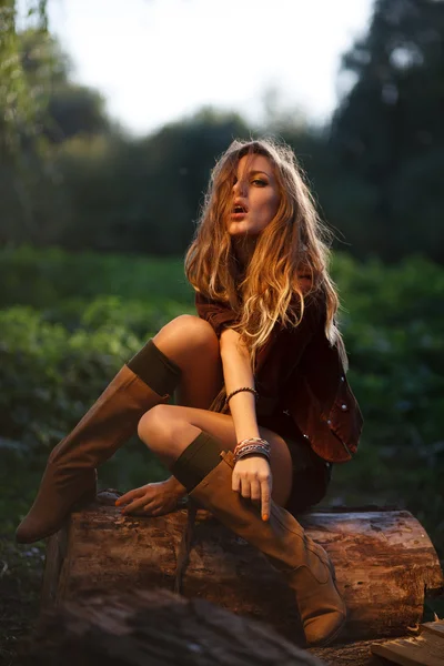 Schöne junge Frau sitzt auf Baumstamm posiert — Stockfoto