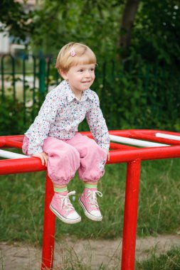 küçük kız oyun alanında oturmuş