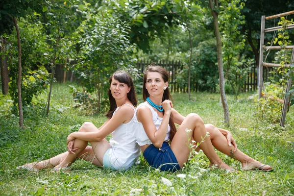 Дві молоді жінки сидять на траві — стокове фото