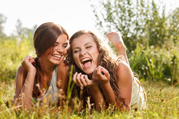 two girlfriends lying down on grass