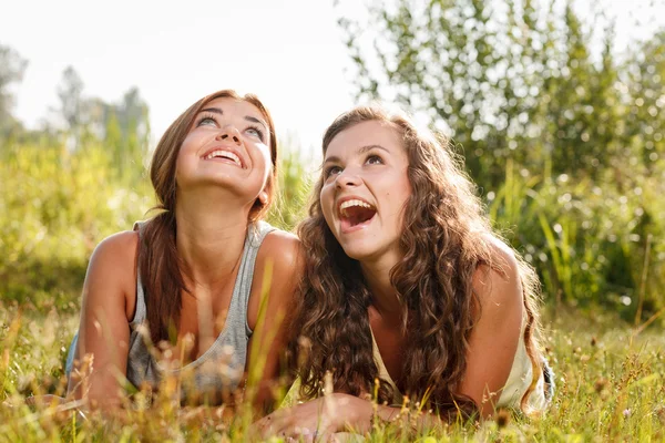 Two girlfriends lying down on grass — Stock Photo, Image