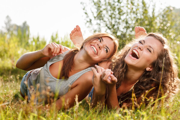 two girlfriends lying down on grass