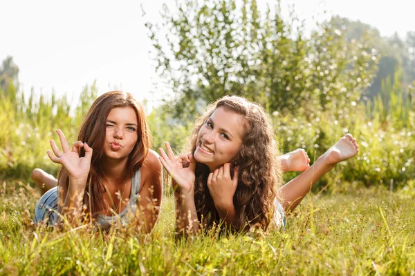 Two girlfriends lying down on grass — Stock Photo, Image