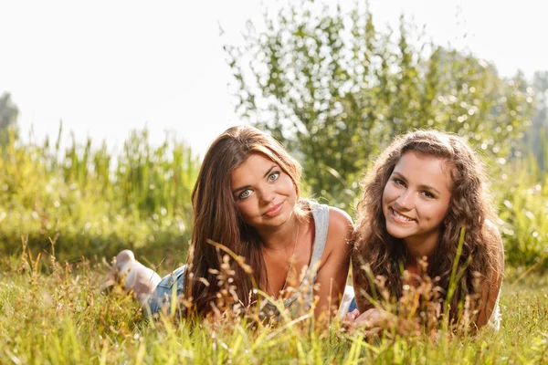 Två flickvänner liggande på gräs — Stockfoto