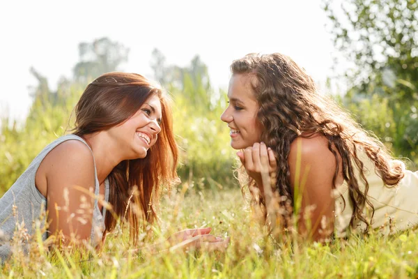 Two girlfriends lying down on grass — Stock Photo, Image