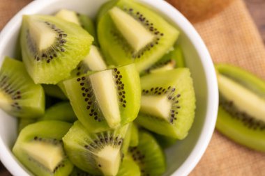 Close-up fresh green kiwis slice in the white bowl on the brown sack