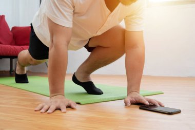 Tişörtlü ve Şortlu Kaslı Sporcu Telefonunda Kronometre Kullanırken Dağ Tırmanışı Egzersizleri Yapıyor. Parlak Oturma Odası 'nda Minimalist İçişleri' nde eğitim görüyor..