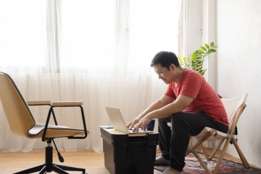 Evde dizüstü bilgisayar kullanan yakışıklı bir adam. Odasında dinlenen adamlar. Çevrimiçi alışveriş, ev işi, serbest çalışma, çevrimiçi öğrenme, öğrenim kavramı. Uzaklık eğitimi