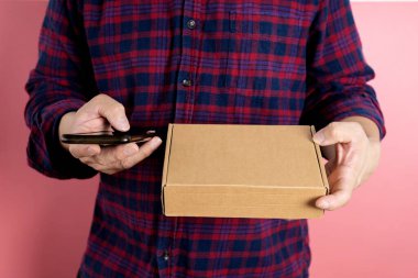 Küçük bir işletme, KOBİ sahipleri, Erkek Girişimciler müşterilere satılacak kutuları hazırlamak için müşterinin adını ve adresini doğrulamak için akıllı telefon kullanarak resim çekiyorlar