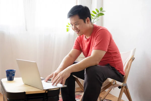 Hombre Barbudo Sonriente Usando Portátil Casa Mientras Está Sentado Mesa —  Fotos de Stock